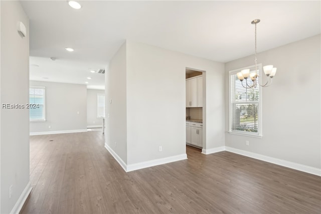 unfurnished room featuring an inviting chandelier and hardwood / wood-style floors