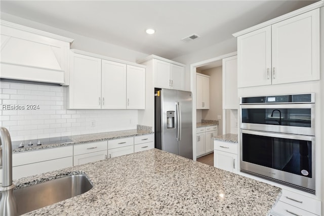 kitchen with sink, white cabinetry, light stone counters, stainless steel appliances, and decorative backsplash