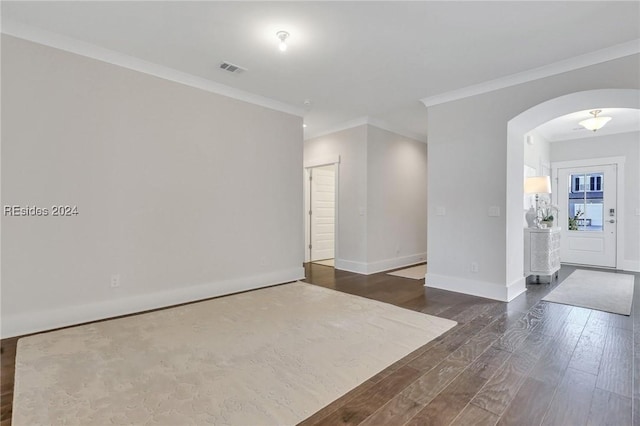 empty room featuring ornamental molding and dark wood-type flooring