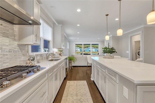 kitchen featuring white cabinetry, sink, pendant lighting, and wall chimney exhaust hood