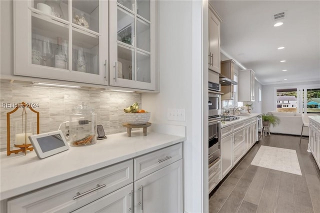 kitchen with double oven, sink, backsplash, white cabinets, and dark hardwood / wood-style flooring