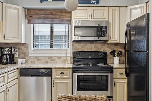 kitchen featuring light stone counters, appliances with stainless steel finishes, and cream cabinetry