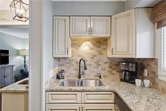 kitchen with sink, decorative backsplash, hanging light fixtures, light stone countertops, and cream cabinetry