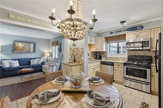 kitchen featuring ornamental molding, appliances with stainless steel finishes, a textured ceiling, and cream cabinets