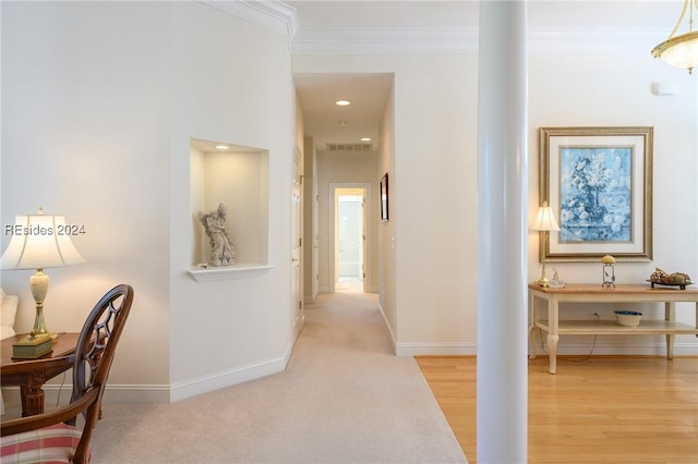 hallway featuring crown molding and light hardwood / wood-style flooring