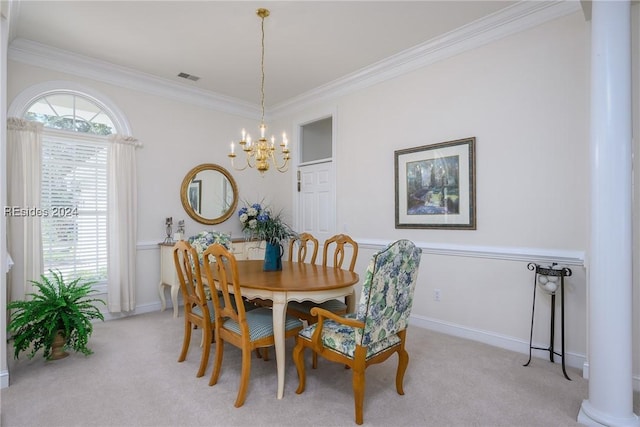 carpeted dining room with decorative columns, crown molding, and an inviting chandelier