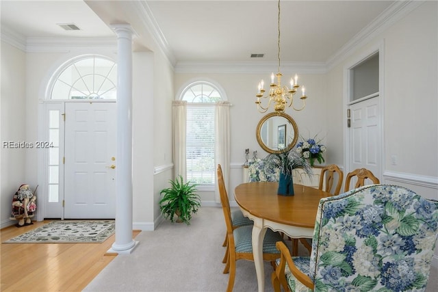 dining area featuring crown molding, light hardwood / wood-style flooring, a chandelier, and ornate columns