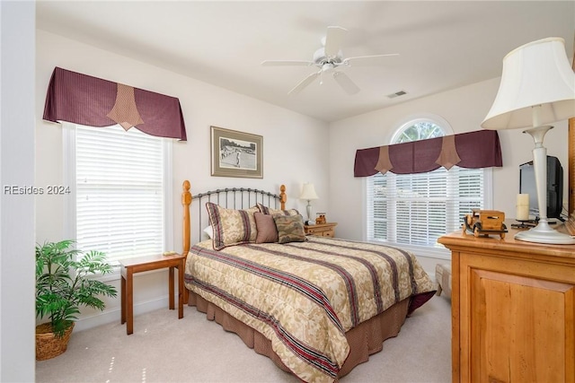 carpeted bedroom featuring multiple windows and ceiling fan