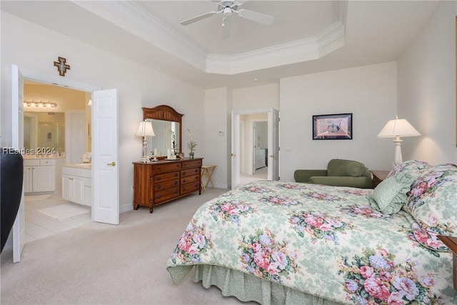 carpeted bedroom featuring ceiling fan, ornamental molding, a raised ceiling, and ensuite bath