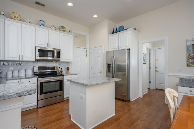 kitchen with light stone countertops, stainless steel appliances, a center island, and white cabinets