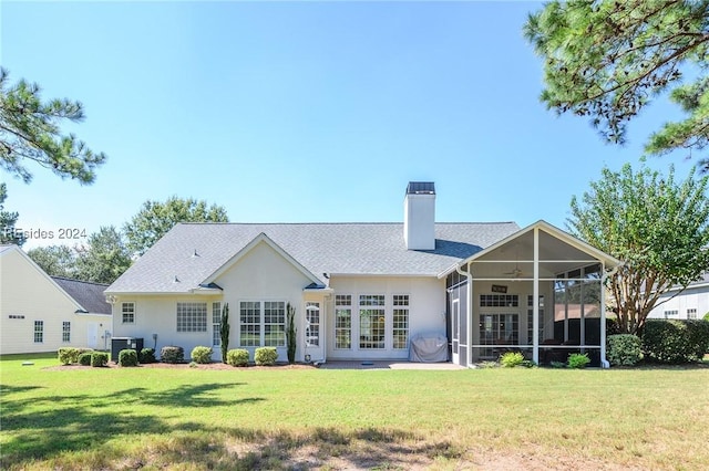 rear view of property featuring central AC unit, a patio area, a sunroom, and a lawn