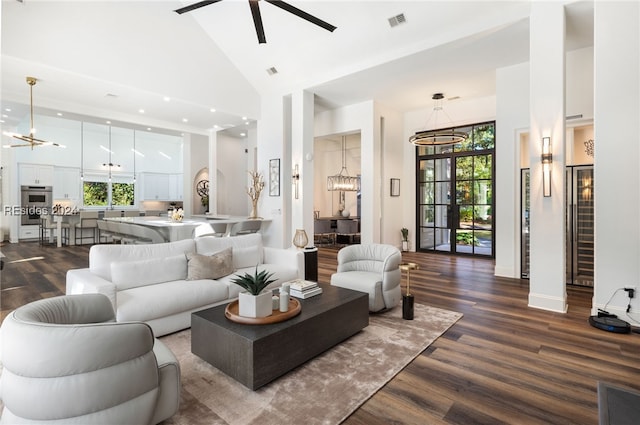 living room with hardwood / wood-style flooring, ceiling fan with notable chandelier, and high vaulted ceiling