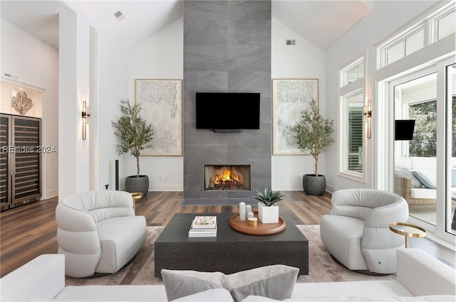 living room with a premium fireplace, hardwood / wood-style floors, and high vaulted ceiling