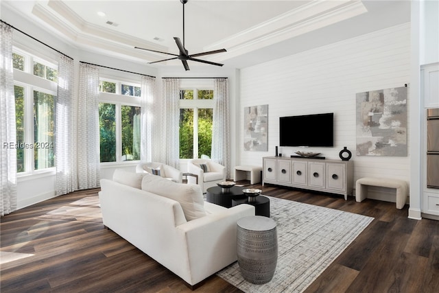 living room featuring ornamental molding, a healthy amount of sunlight, dark hardwood / wood-style flooring, and a tray ceiling