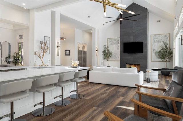 living room with a tiled fireplace, dark hardwood / wood-style flooring, a wealth of natural light, and high vaulted ceiling