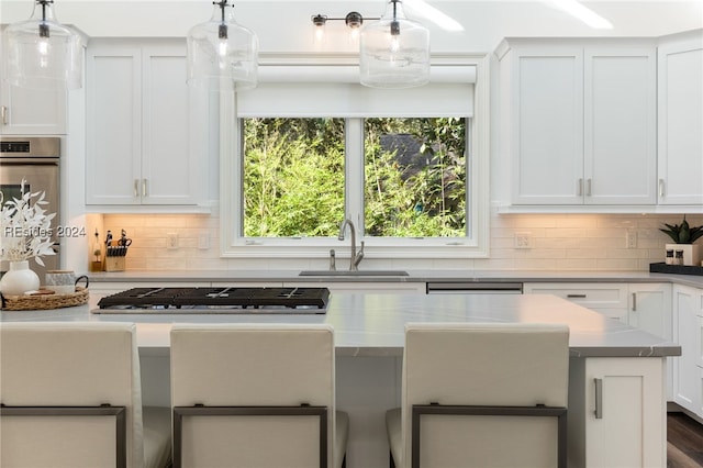 kitchen with hanging light fixtures, appliances with stainless steel finishes, sink, and white cabinets