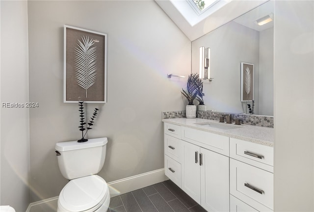 bathroom featuring toilet, vanity, and lofted ceiling with skylight