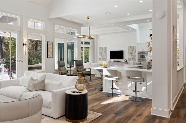 living room with a notable chandelier, dark wood-type flooring, and a healthy amount of sunlight