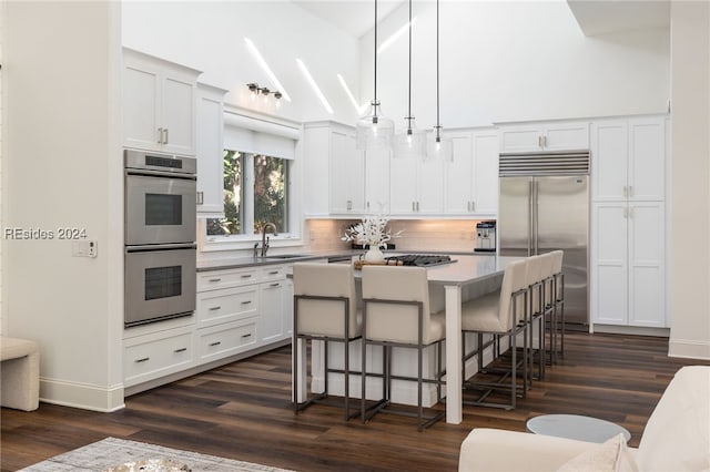 kitchen featuring a kitchen island, appliances with stainless steel finishes, pendant lighting, white cabinetry, and a breakfast bar area