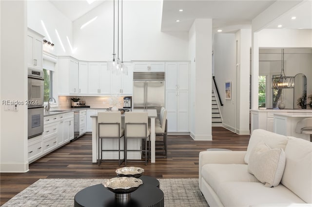 kitchen with sink, a kitchen island, a notable chandelier, pendant lighting, and white cabinets