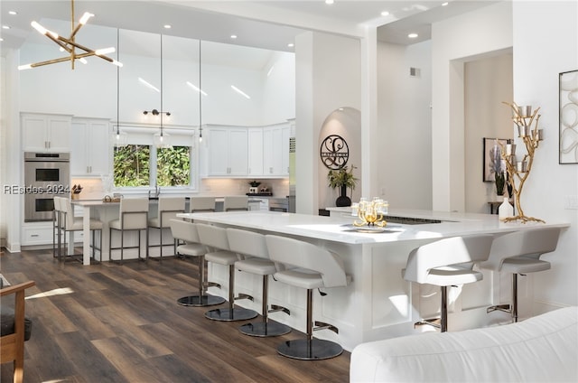 kitchen with double oven, a breakfast bar area, kitchen peninsula, and white cabinets