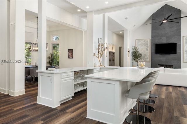 kitchen featuring dark wood-type flooring, white cabinetry, a center island, kitchen peninsula, and ceiling fan with notable chandelier