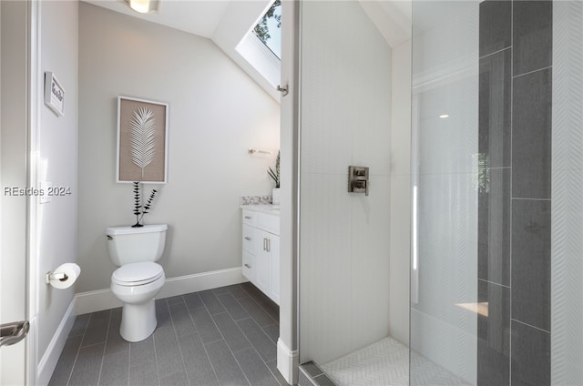 bathroom featuring tiled shower, vanity, vaulted ceiling, tile patterned floors, and toilet