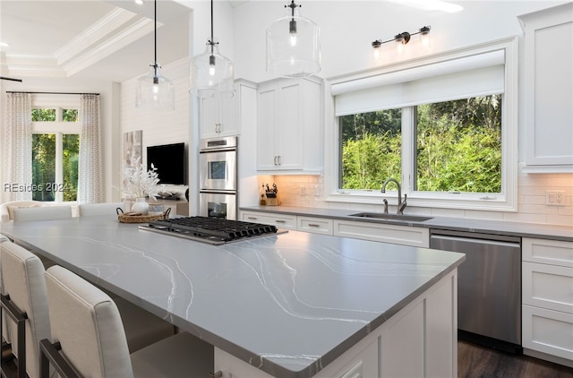 kitchen featuring appliances with stainless steel finishes, dark stone countertops, white cabinets, and decorative light fixtures