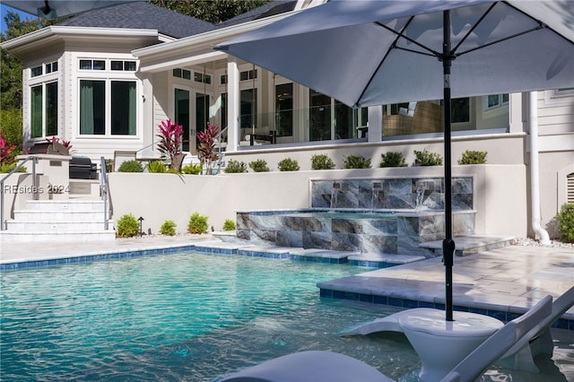 view of swimming pool with pool water feature, exterior kitchen, and a patio