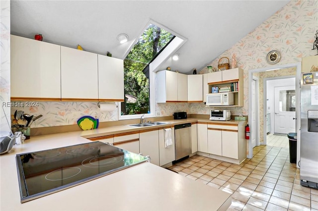 kitchen with appliances with stainless steel finishes, sink, light tile patterned floors, and white cabinets