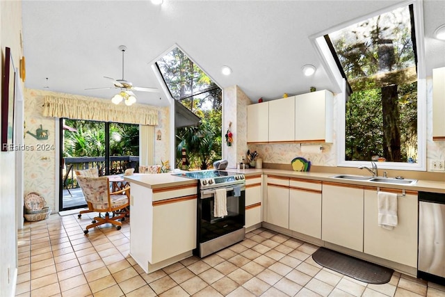 kitchen featuring sink, light tile patterned floors, kitchen peninsula, stainless steel appliances, and vaulted ceiling with skylight