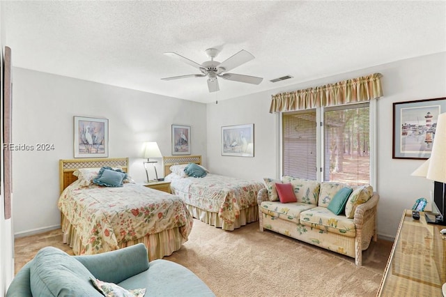 bedroom featuring light colored carpet, a textured ceiling, and ceiling fan