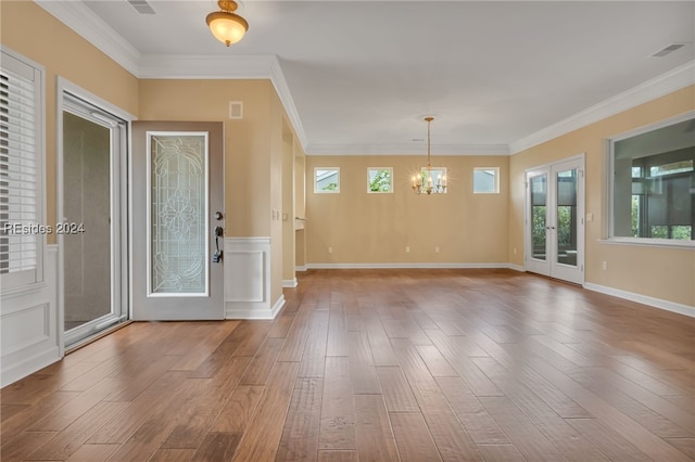 foyer featuring hardwood / wood-style flooring, ornamental molding, an inviting chandelier, and french doors