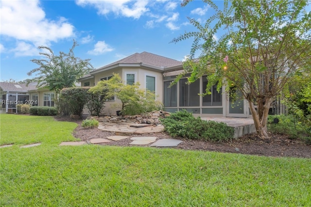 back of property with a yard and a sunroom