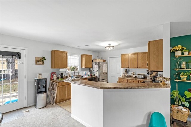 kitchen with light colored carpet, kitchen peninsula, and stainless steel refrigerator