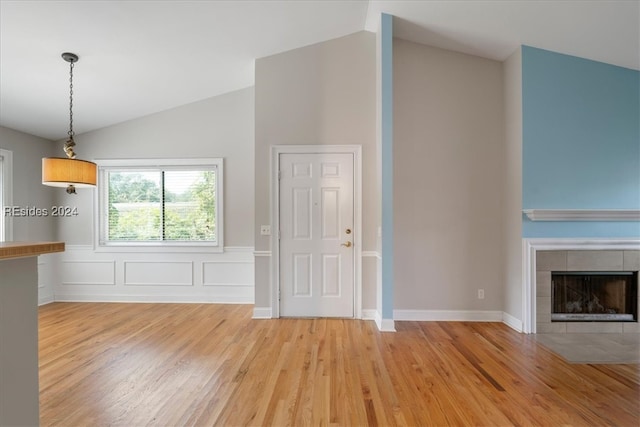 unfurnished living room featuring a fireplace, vaulted ceiling, and light hardwood / wood-style floors