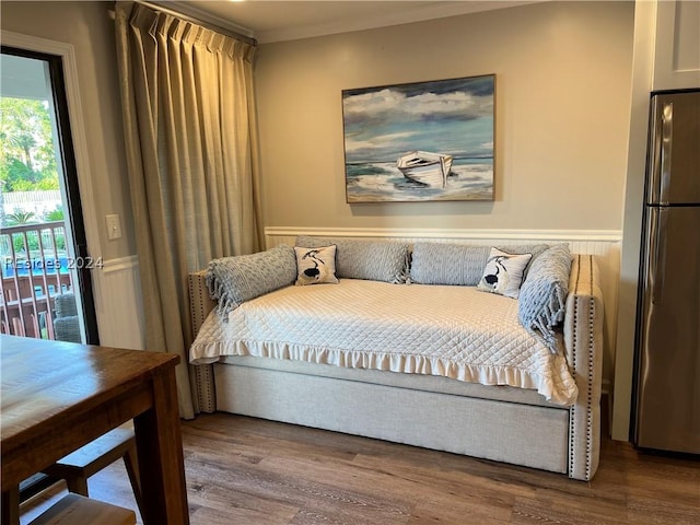 bedroom featuring access to exterior, hardwood / wood-style flooring, and stainless steel refrigerator