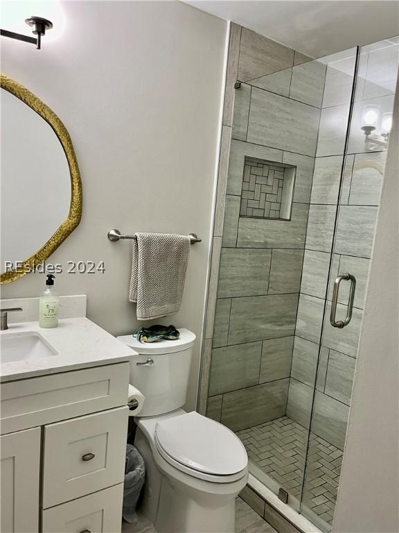 bathroom with vanity, toilet, and a shower with door