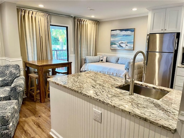 kitchen featuring white cabinetry, sink, stainless steel fridge, and light stone countertops