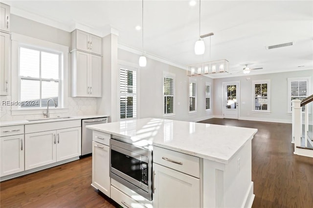 kitchen with decorative backsplash, stainless steel appliances, hanging light fixtures, and white cabinets