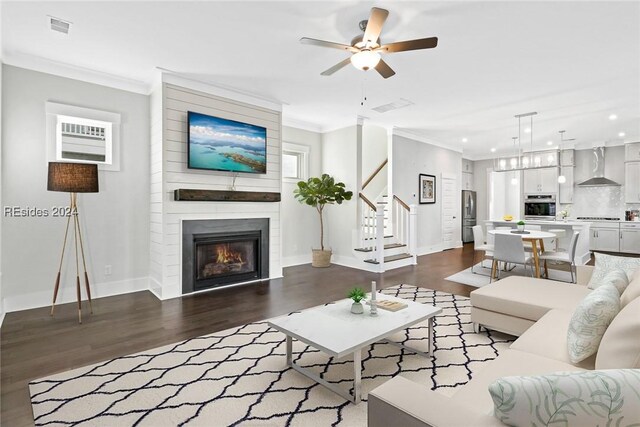 living room with crown molding, dark wood-type flooring, ceiling fan, and a fireplace