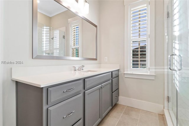 bathroom featuring a healthy amount of sunlight, vanity, a shower with door, and tile patterned flooring