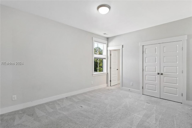 unfurnished bedroom with light colored carpet and a closet