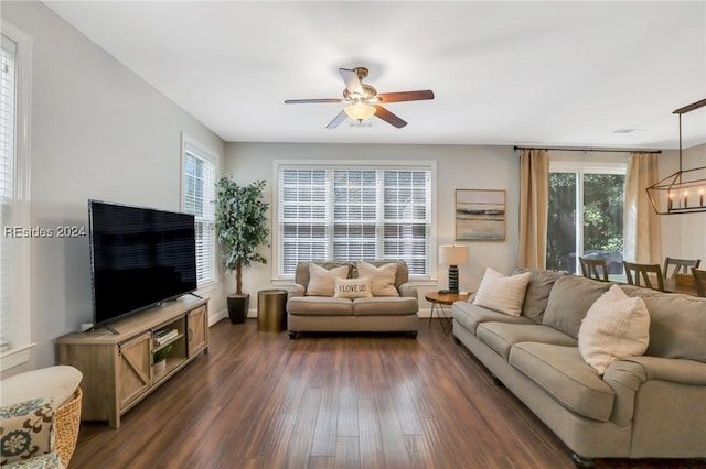 living room featuring dark wood-type flooring and ceiling fan with notable chandelier