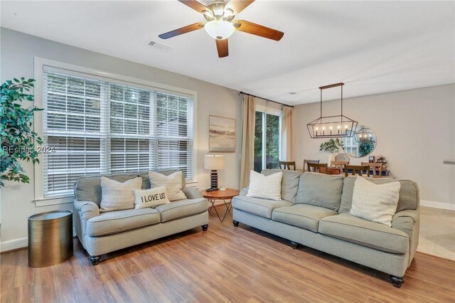 living room with wood-type flooring and ceiling fan with notable chandelier