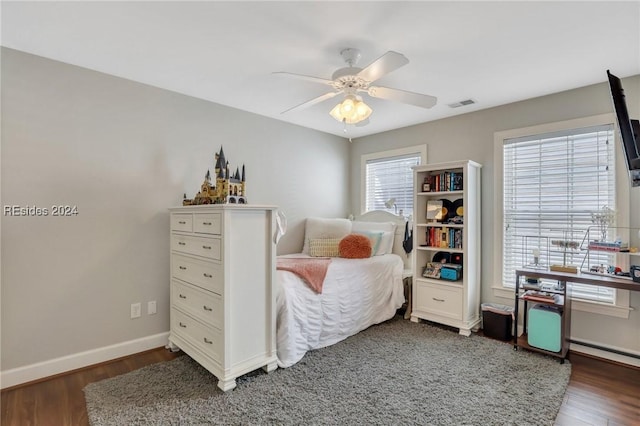 bedroom featuring ceiling fan, dark hardwood / wood-style floors, and multiple windows