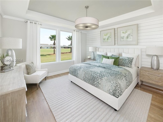 bedroom featuring hardwood / wood-style floors, crown molding, and a raised ceiling