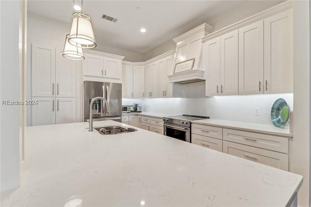 kitchen featuring hanging light fixtures, stainless steel appliances, sink, and white cabinets