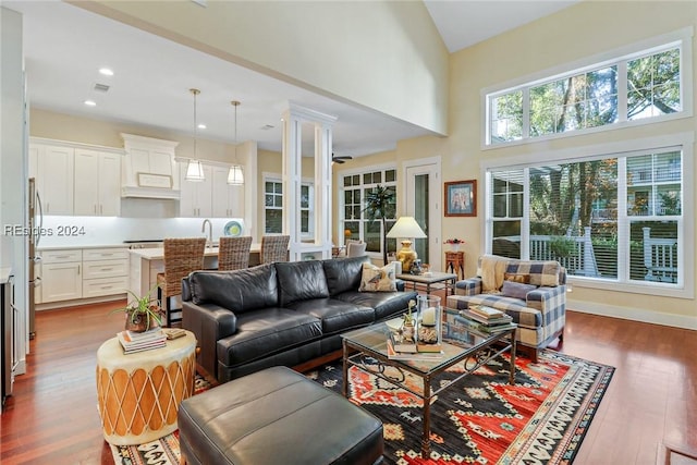 living room featuring decorative columns, sink, dark hardwood / wood-style flooring, and a towering ceiling