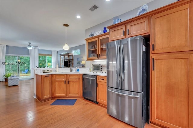 kitchen with decorative light fixtures, appliances with stainless steel finishes, kitchen peninsula, ceiling fan, and light hardwood / wood-style floors